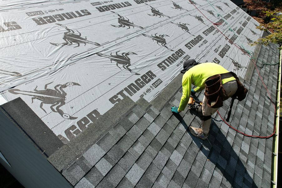 Roofer nailing shingles along the starter course