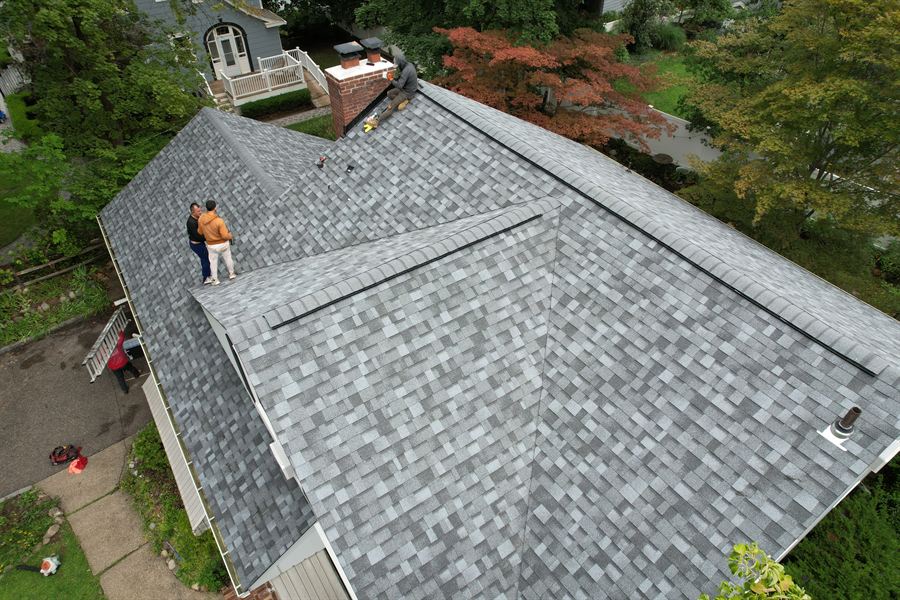 Two Pro Gen roofers on a newly installed gray shingle roof
