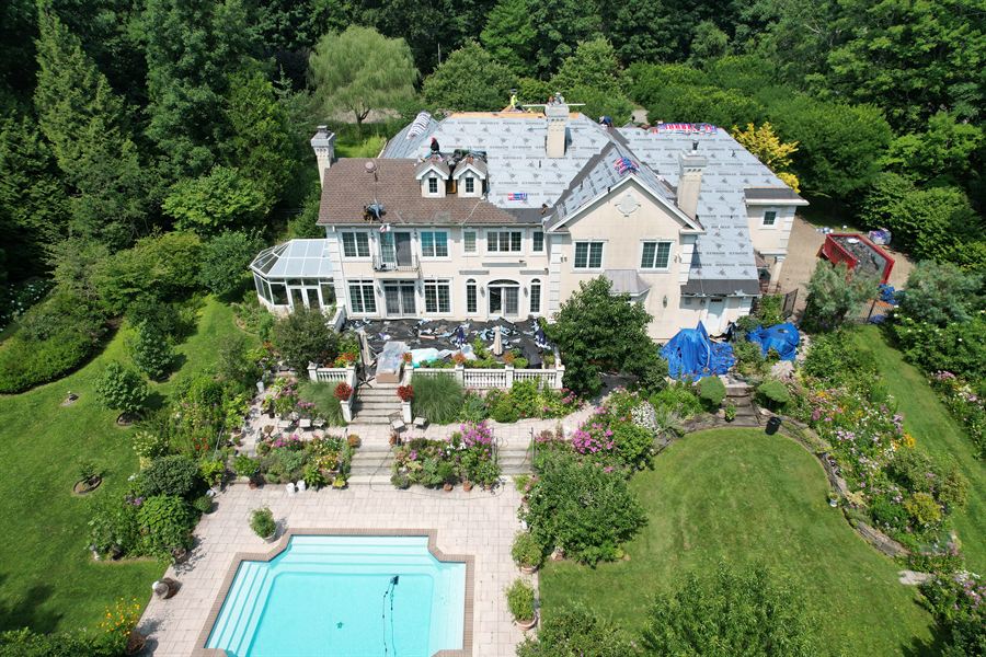 Large New Jersey home mid-replacement with underlayment installed, drone view over the backyard pool