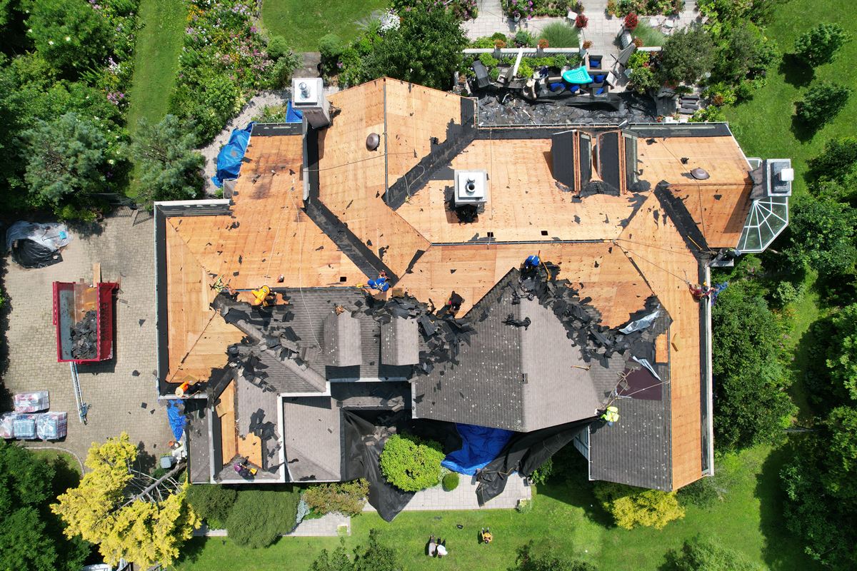Drone view of a full roof tear-off exposing the bare plywood sheathing